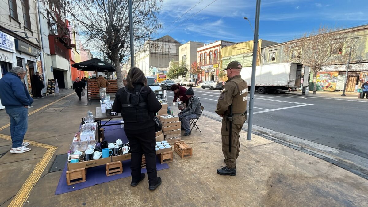 Personal de Carabineros y Seguridad Ciudadana fiscalizando puestos de comercio informal en la vía pública.