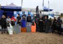 Grupo de jóvenes deportistas posando con sus trofeos y tablas en la arena de Playa El Bato, Quintero.
