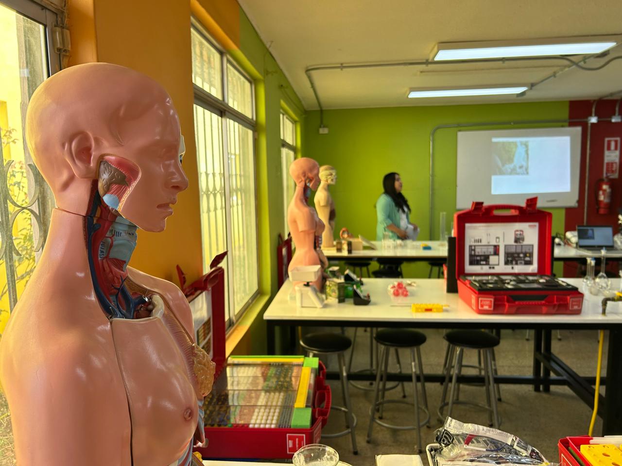 Interior del laboratorio escolar con maquetas de anatomía humana y equipo de medición.
