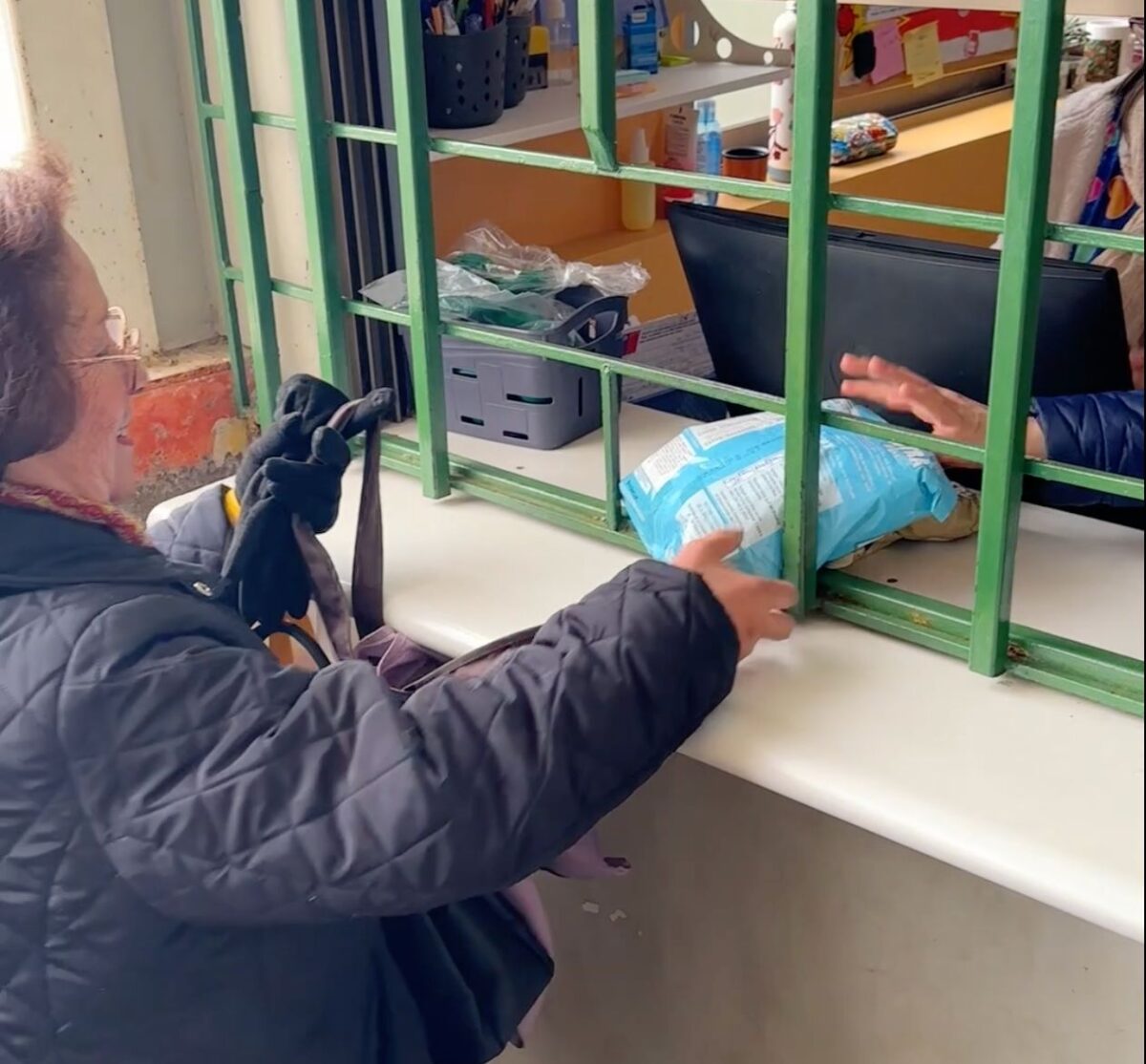 Beneficiaria retirando paquete de leche en puesto de atención primaria.