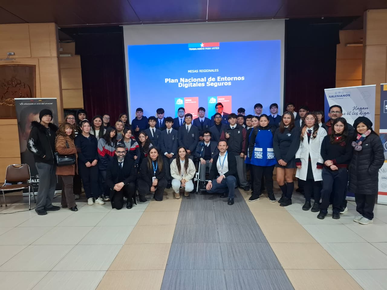 Grupo de estudiantes y autoridades posando frente a una pantalla con el Plan Nacional de Entornos Digitales Seguros.