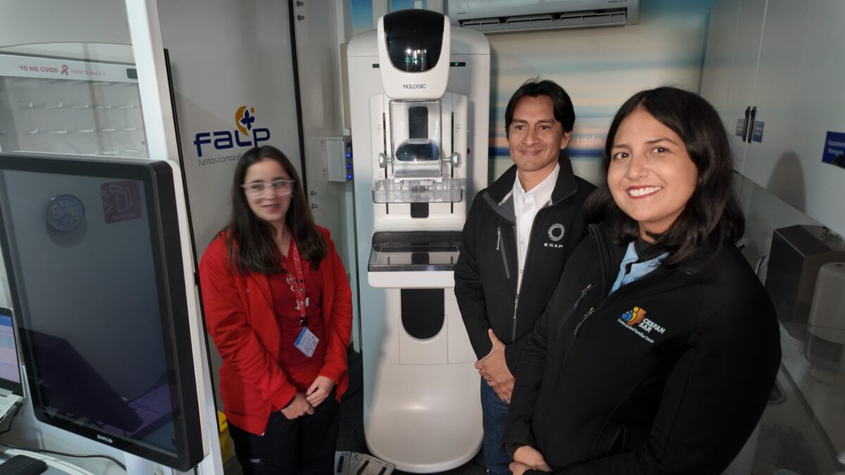 Personal de salud junto a equipamiento de mamografía en clínica móvil.