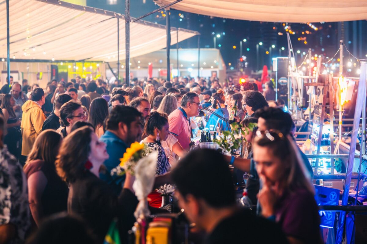 Vista aérea de una gran concentración de personas en Expovino, con puestos iluminados y ambiente festivo.
