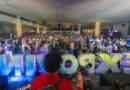 Una multitud animada disfruta de un concierto con un escenario luminoso y letras grandes de 'EXPOVI'.