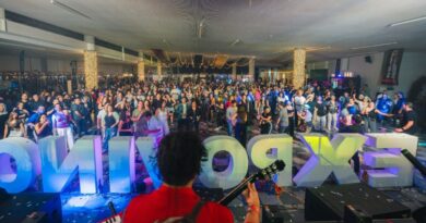 Una multitud animada disfruta de un concierto con un escenario luminoso y letras grandes de 'EXPOVI'.