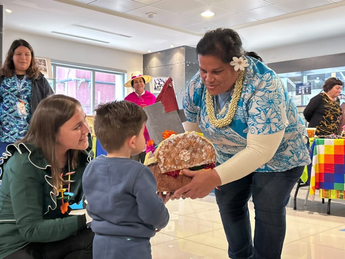 Representante Rapa Nui entregando una muestra cultural a un niño en la feria.
