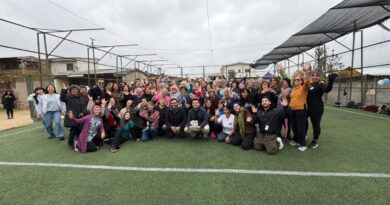 Grupo de personas posando en una cancha de pasto sintético durante la Feria de la Familia y el Cuidado Mutuo en Villa Alemana.