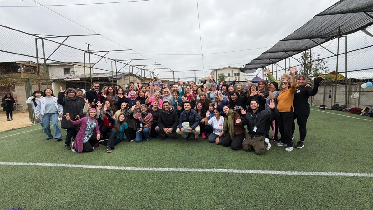 Grupo de personas posando en una cancha de pasto sintético durante la Feria de la Familia y el Cuidado Mutuo en Villa Alemana.
