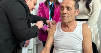 Hombre siendo vacunado por personal de salud, con autoridades observando la acción.