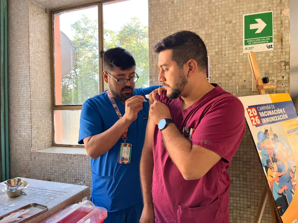 Enfermero aplicando una vacuna a un colega.