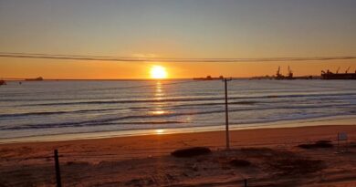 Puesta de sol sobre el mar con barcos a lo lejos, vista desde el tren del recuerdo.