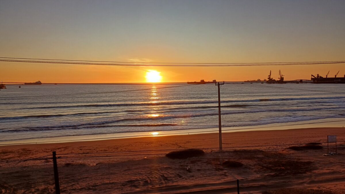 Puesta de sol sobre el mar con barcos a lo lejos, vista desde el tren del recuerdo.