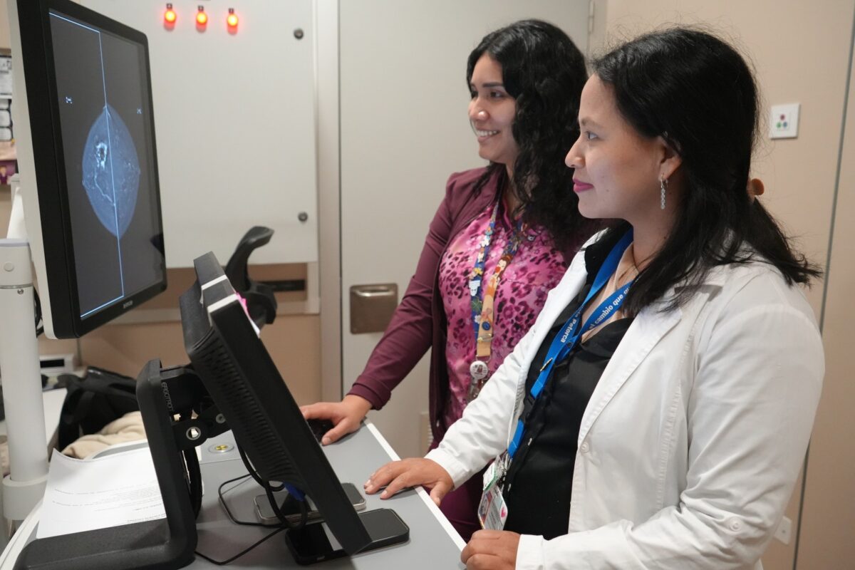 Dos profesionales de la salud observando una pantalla con imágenes mamarias.