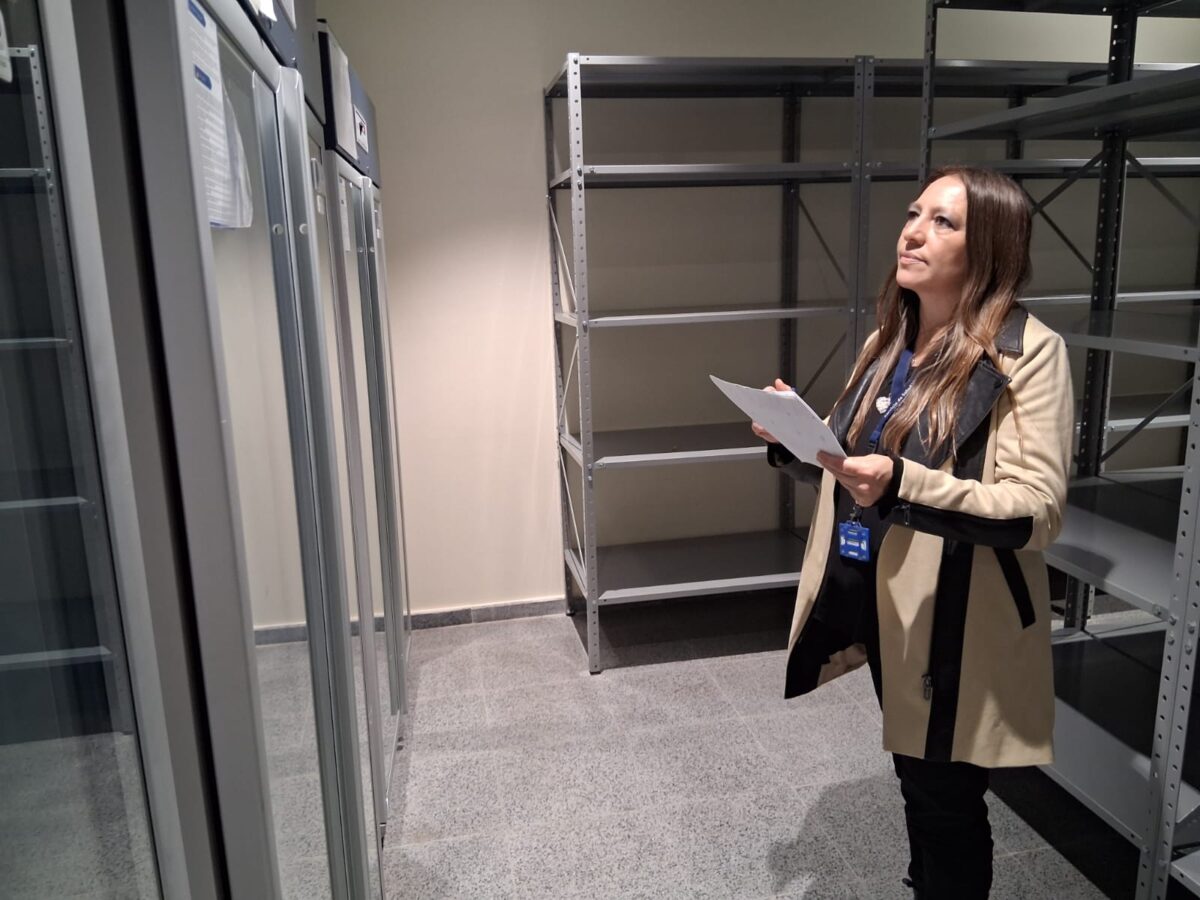 Mujer revisando documentación en una sala con estanterías y equipos.