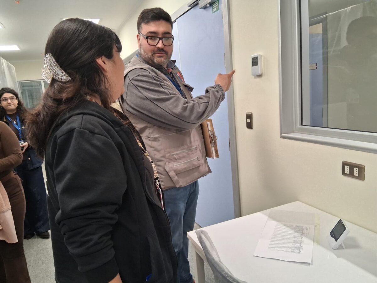 Hombre señalando un dispositivo en la pared mientras habla con una mujer.