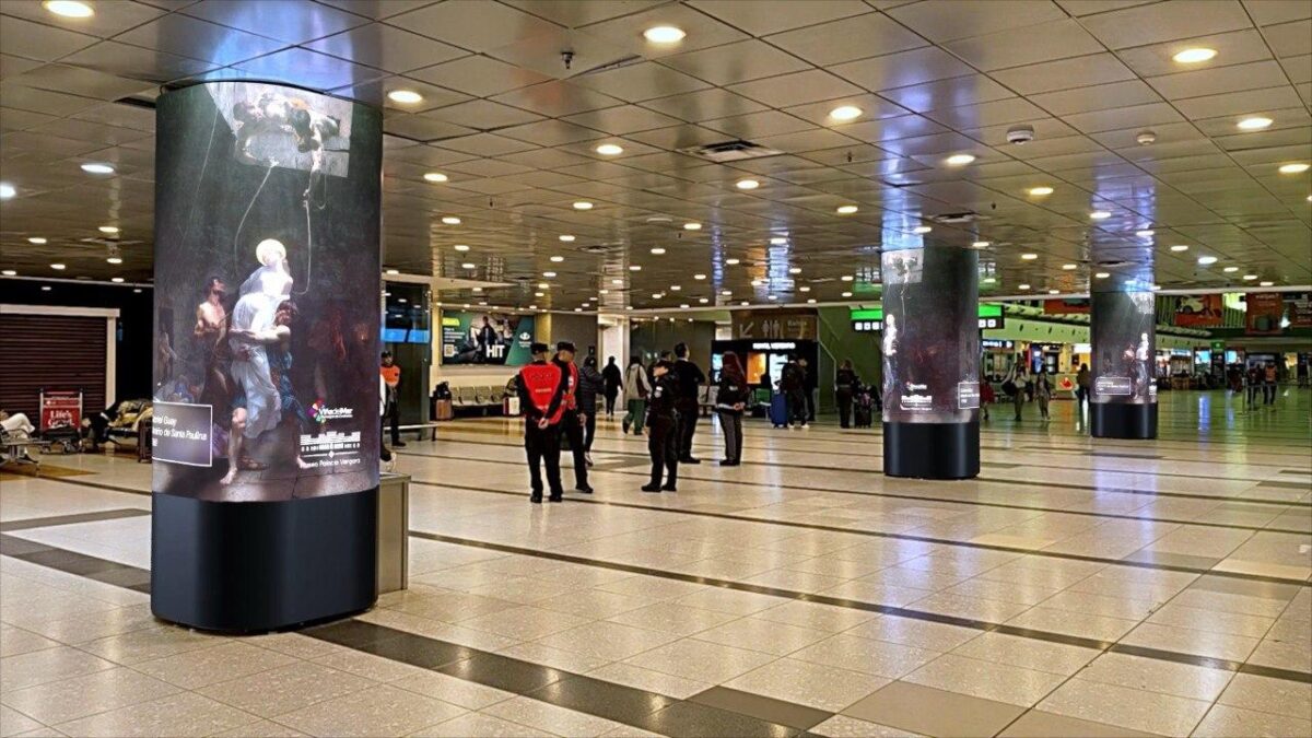 Vista interior de un aeropuerto con una columna digital exhibiting obras de arte.