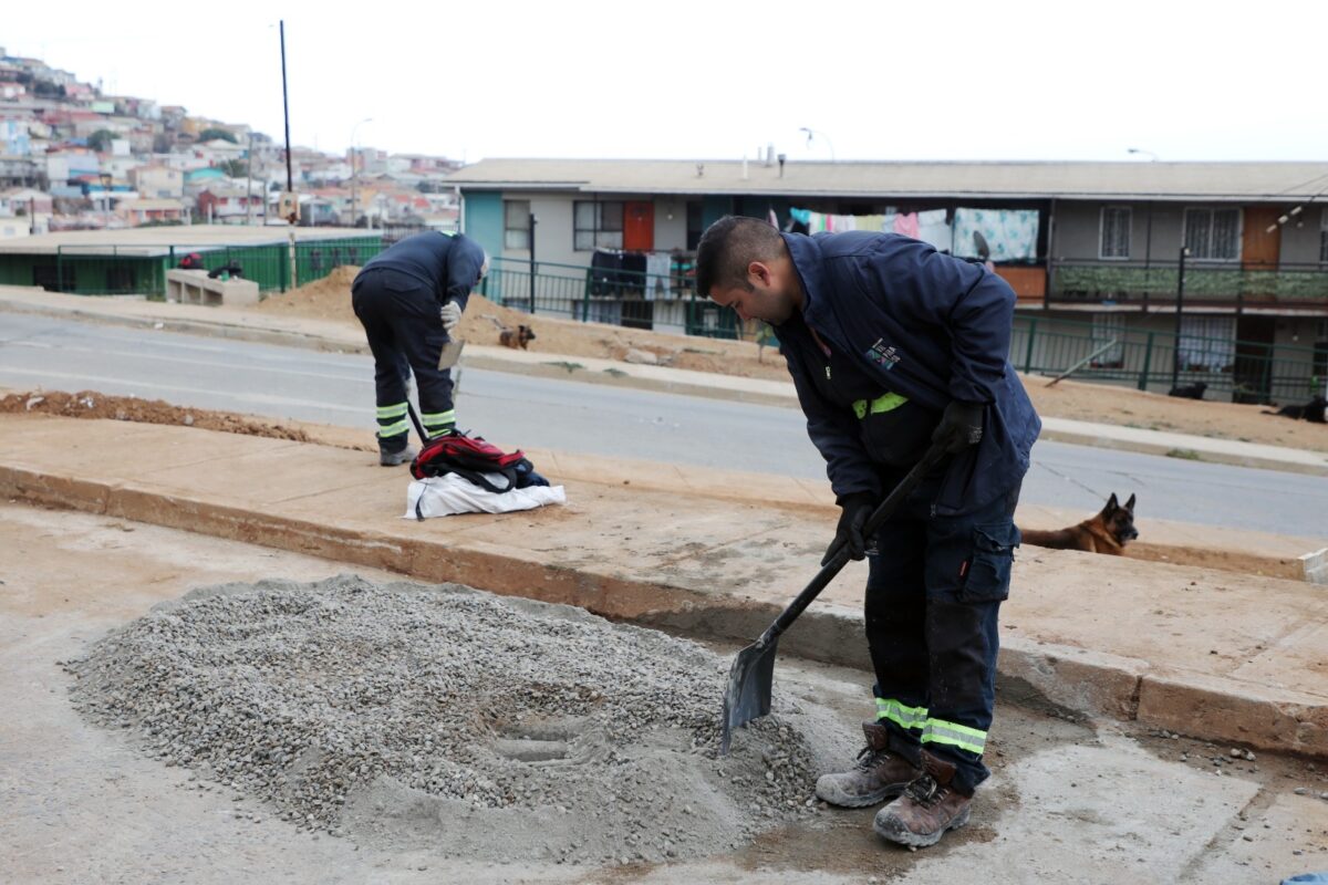 Trabajadores municipales mezclan material de construcción en la vía pública como parte de obras de mejoramiento.