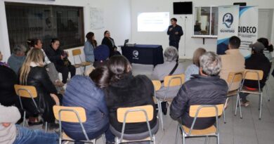 Grupo de personas asistiendo a una charla en un salón comunal.