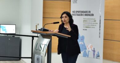 Una mujer habla desde un atril durante un evento de la Universidad Santo Tomás.