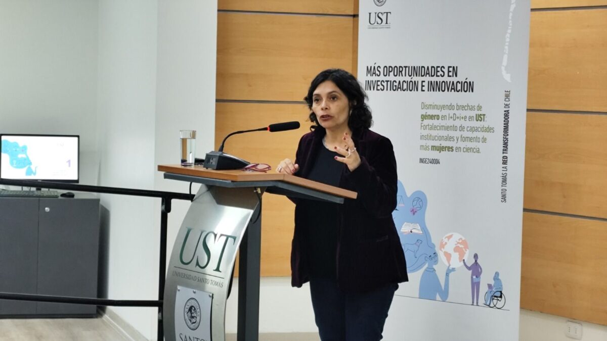 Una mujer habla desde un atril durante un evento de la Universidad Santo Tomás.