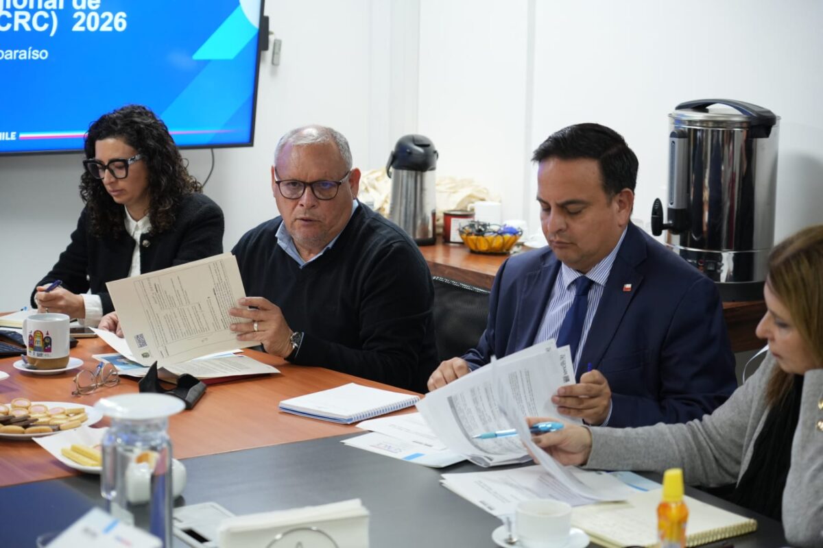 Personas sentadas alrededor de una mesa revisando documentos.