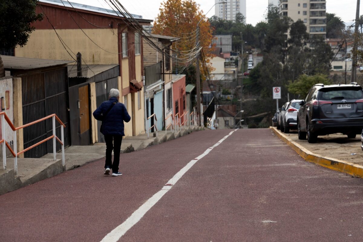 Persona caminando por la calle de acceso al Cesfam Esperanza, Valparaíso, que presenta un nuevo tratamiento de alta fricción.