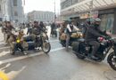 Grupo de personas posando frente a un cartel con temática de motociclismo y prevención de salud.