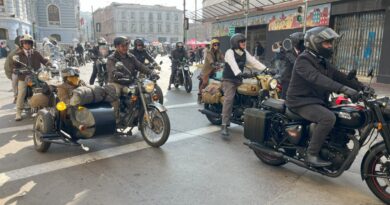 Grupo de personas posando frente a un cartel con temática de motociclismo y prevención de salud.