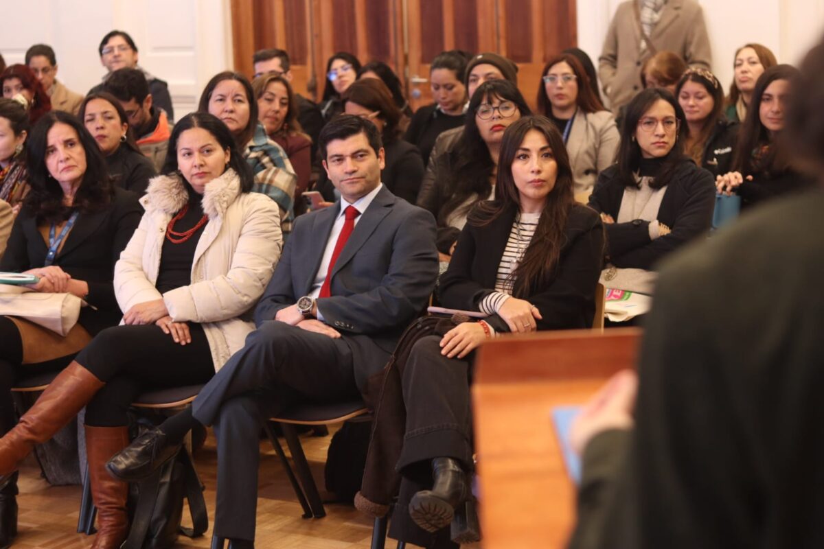 Participantes sentados en un seminario, con un hombre en traje en primer plano.