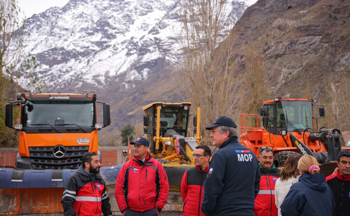 Grupo de trabajadores del MOP y maquinaria pesada en un entorno montañoso.