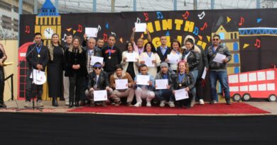 Estudiantes y docentes posan con certificados y medallas en un escenario decorado con motivos de Londres durante el English Song Festival.