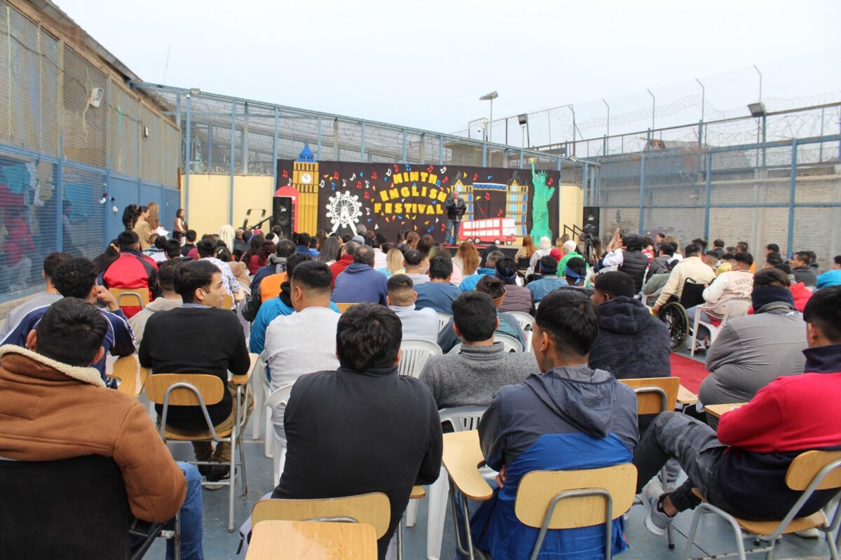 Vista panorámica de la audiencia asistiendo al English Song Festival desde sillas dispuestas en el patio del centro de detención.