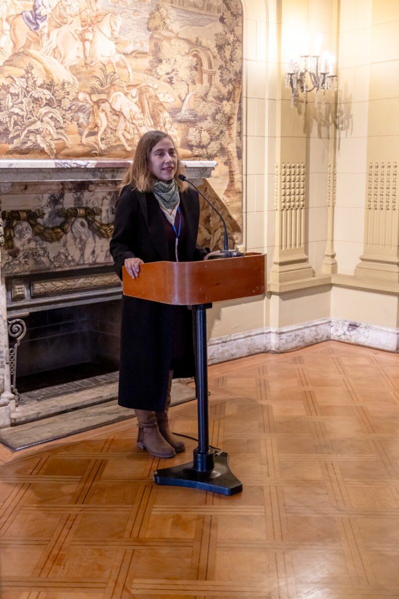 Una mujer de pie en un atril dando una presentación en la XIII Bienal Internacional de Artes de Valparaíso.