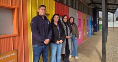 Cuatro personas posan frente a un edificio con coloridas paredes exteriores.