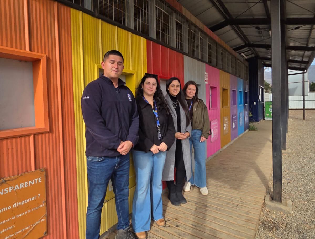 Cuatro personas posan frente a un edificio con coloridas paredes exteriores.