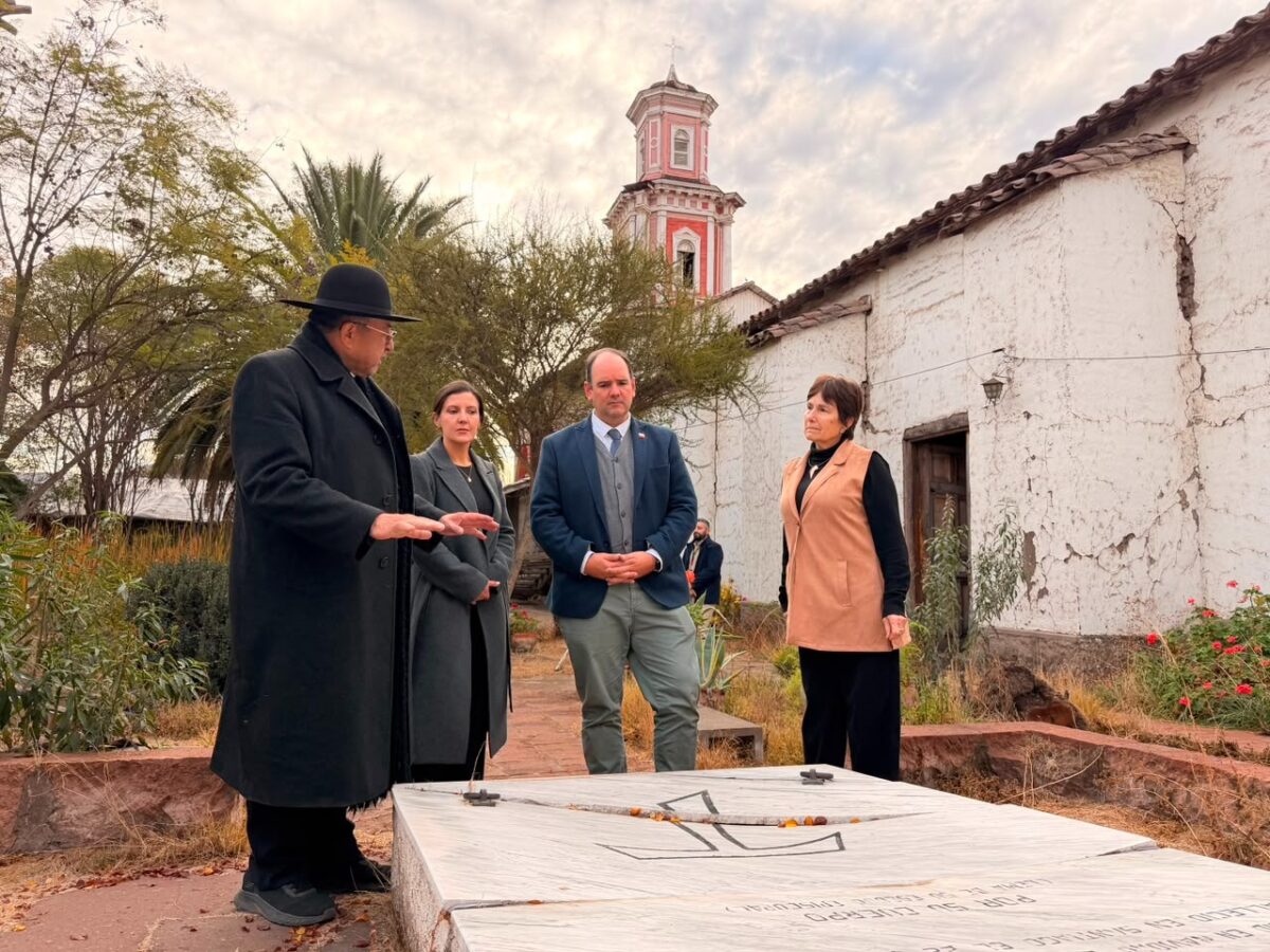 Autoridades observan una tumba o monumento en el exterior de la Iglesia San Francisco de Curimón, con la torre de la iglesia al fondo.