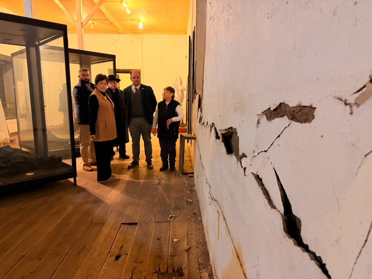 Grupo de autoridades y funcionarios observan el interior de la Iglesia San Francisco de Curimón, prestando atención a una pared dañada.
