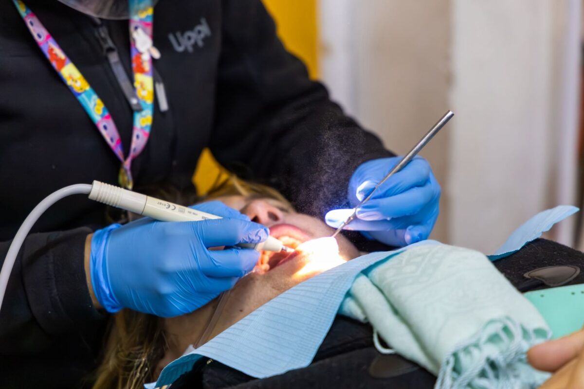 Primer plano de una dentista realizando un procedimiento dental a un paciente, con guantes azules.