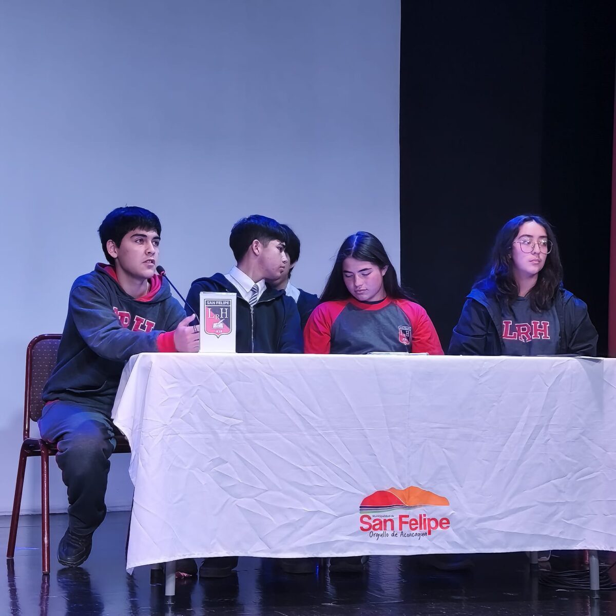 Estudiantes participan en un debate sentados en una mesa.