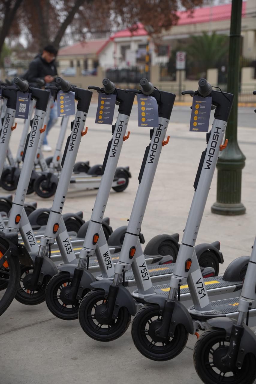 Primer plano de manubrios y partes delanteras de scooters eléctricos grises de la empresa Whoosh.
