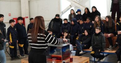 Estudiantes observando un experimento sobre dinámica de fluidos dirigido por una profesora en una sala de clases.