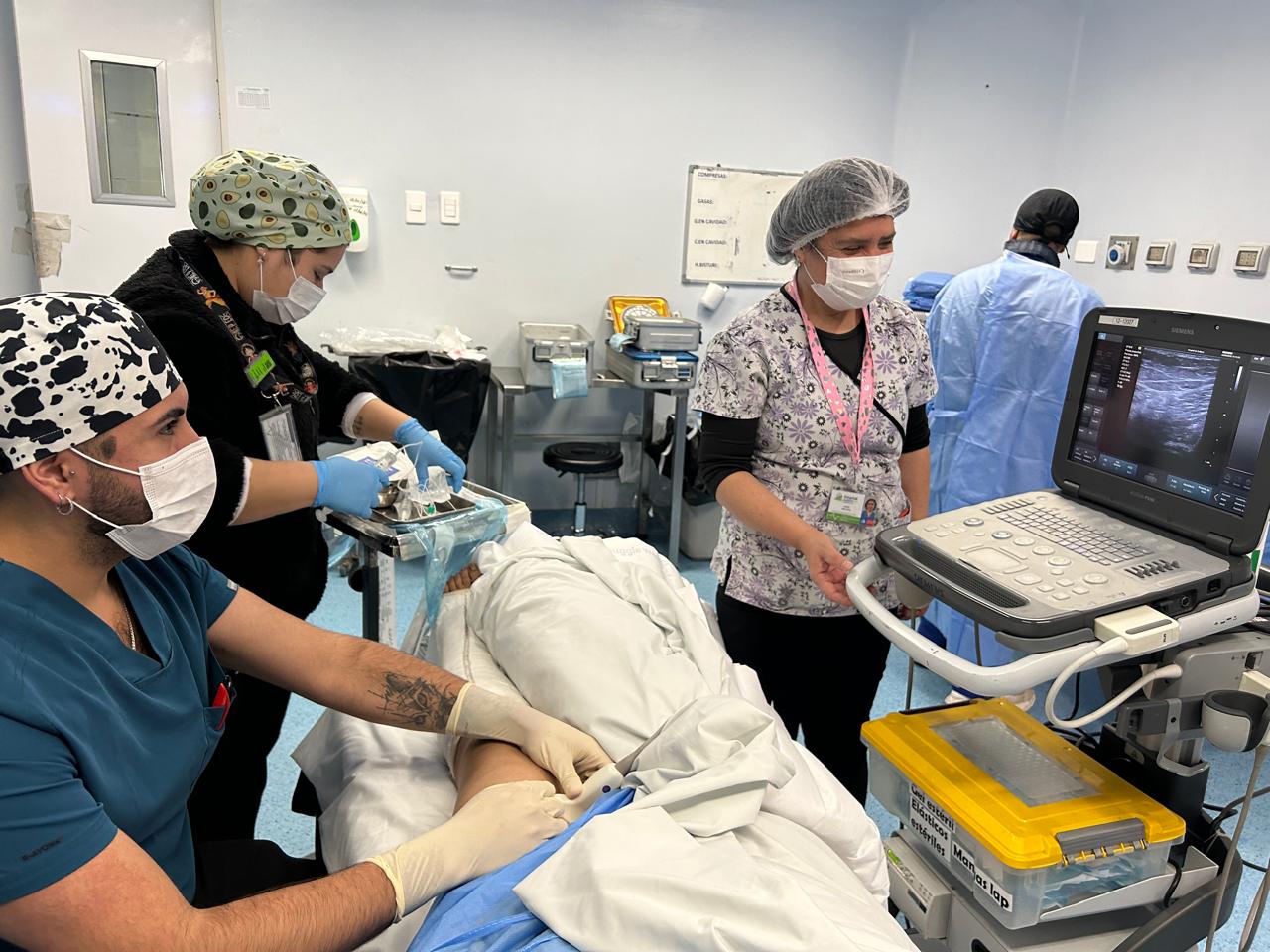 Equipo médico trabajando en un procedimiento de ecografía en una sala de hospital.