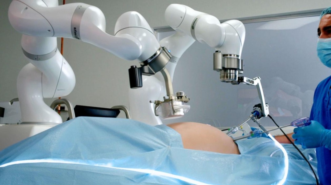 Cirujano observa a un robot quirúrgico asistiendo en una operación laparoscópica.