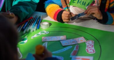 Niños participando en una actividad creativa con materiales sobre una mesa verde.