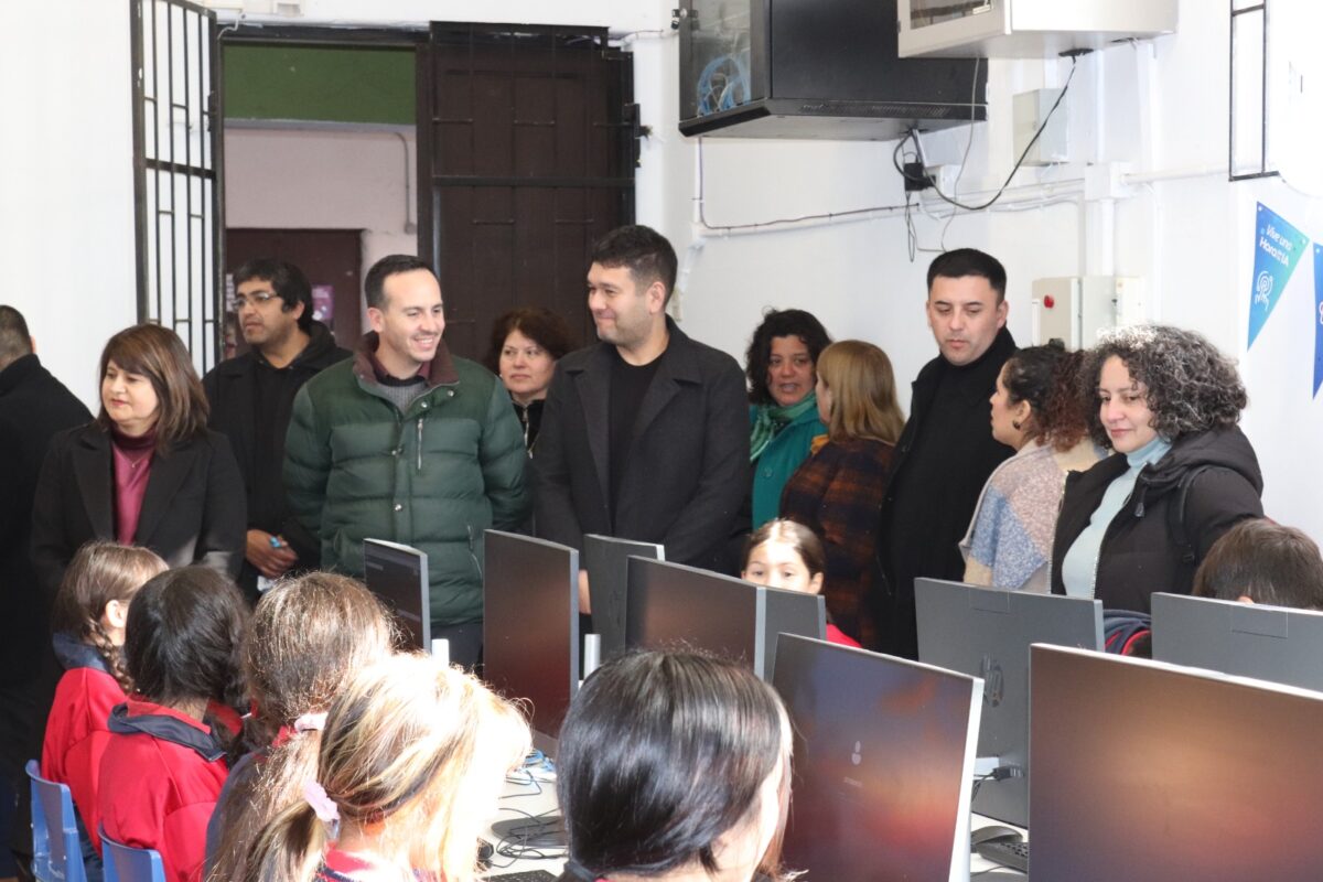 Grupo de adultos observando a estudiantes en un laboratorio de computación.