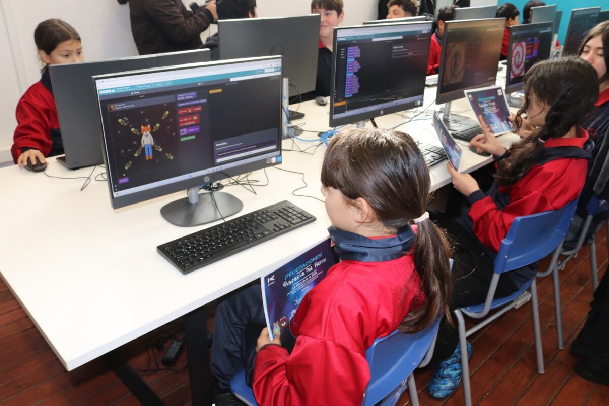 Estudiantes trabajando en computadoras en un aula.
