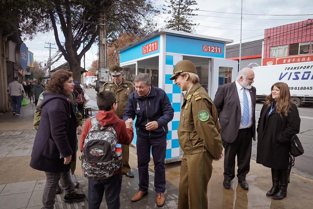 El alcalde Nelson Estay y la General Patricia Vásquez conversan con un niño y vecinos en el centro de Villa Alemana junto a un punto de seguridad.