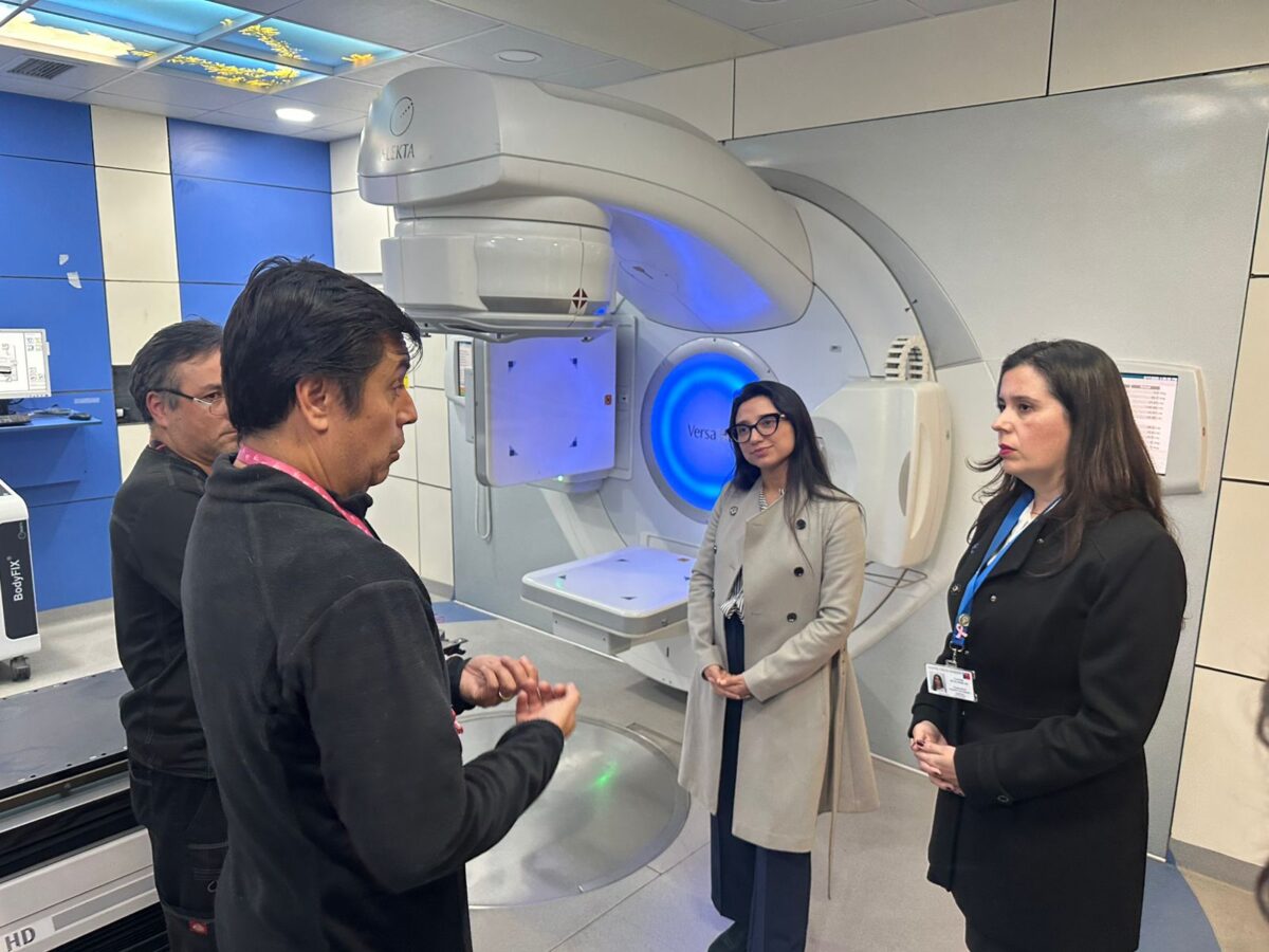 La Seremi de Salud de Valparaíso, Dra. Mariol Luan, junto a profesionales del área médica conversando frente a equipamiento oncológico de alta tecnología.