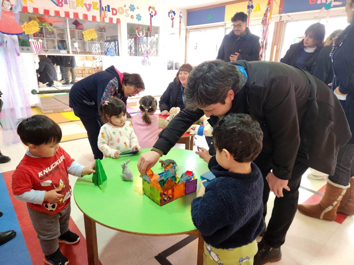 Niños y autoridades interactuando con juegos didácticos en el Jardín Infantil Pequeño Paraíso.