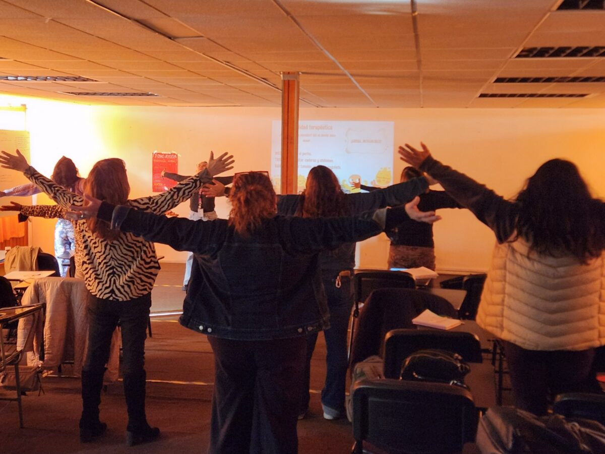 Participantes del taller de salud mental con los brazos extendidos realizando ejercicios de relajación corporal.